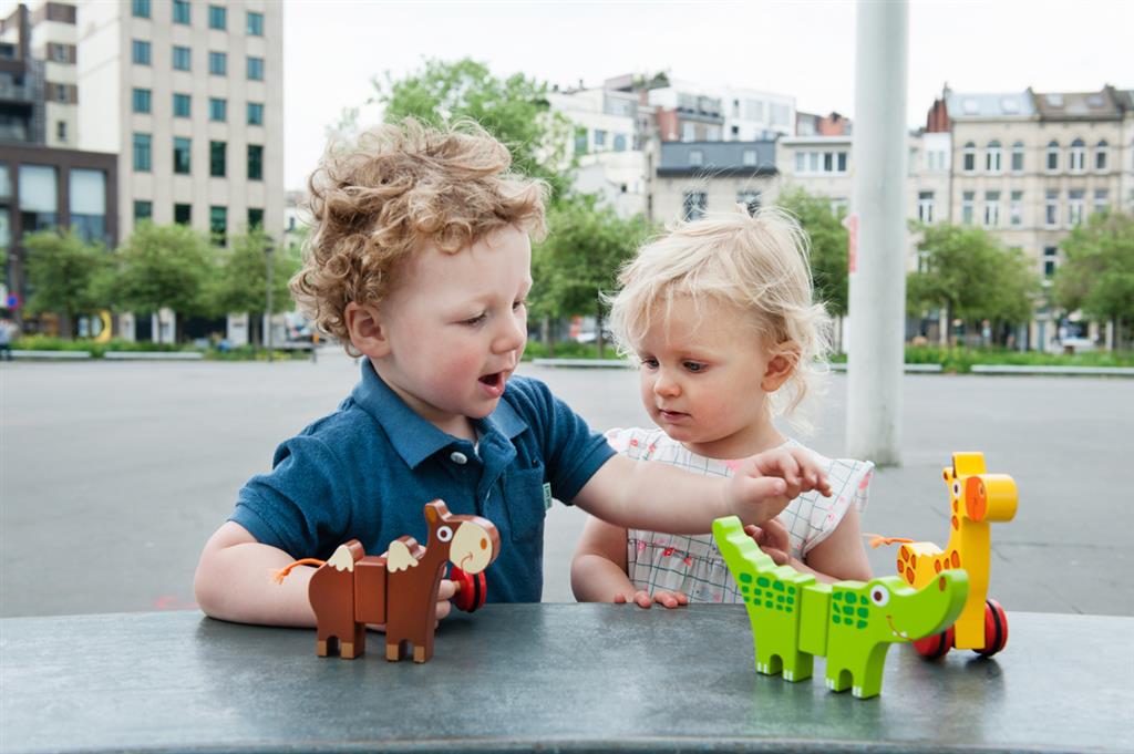 Two kids playing with magnetic animal toys in a park, enjoying their colorful safari adventures.